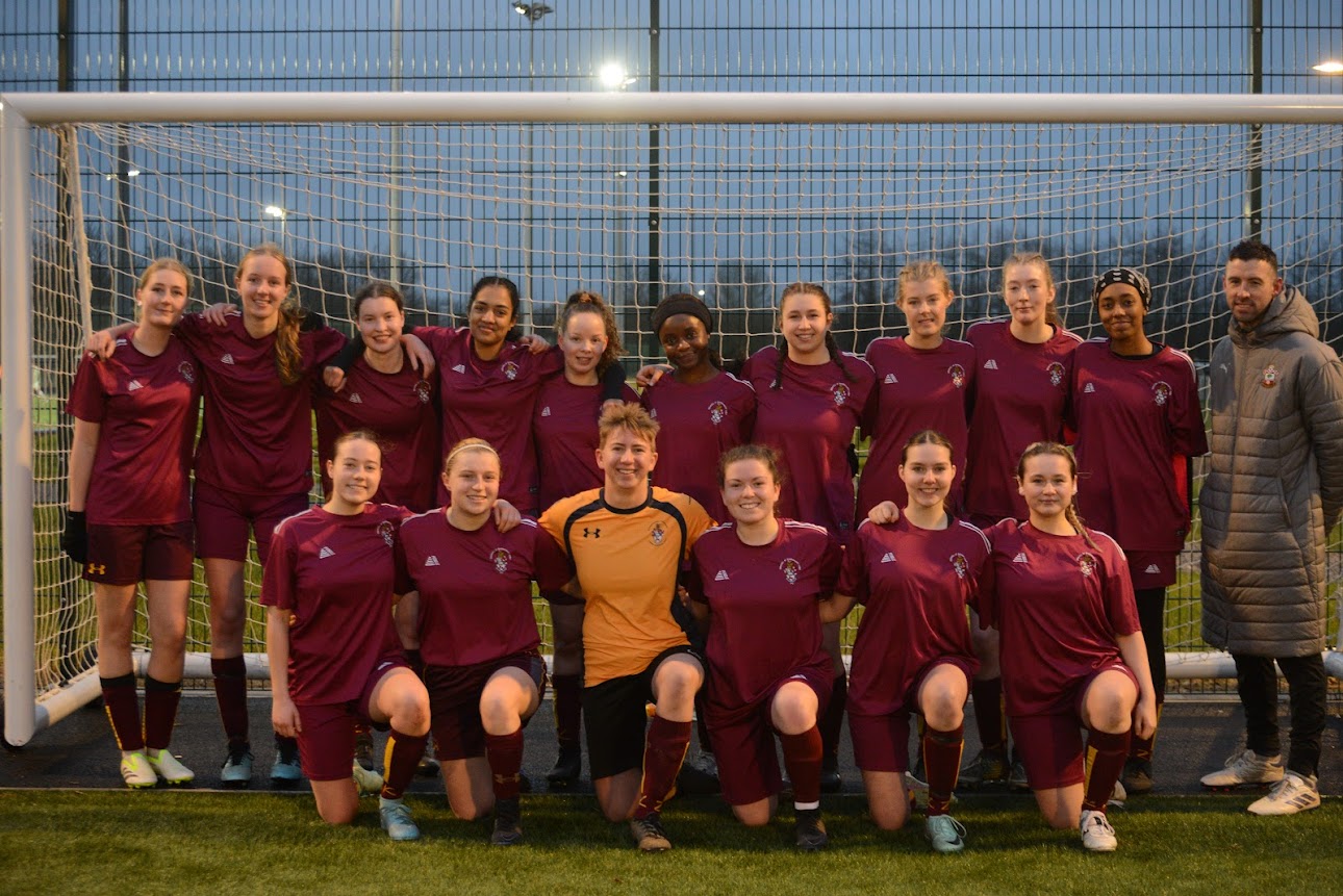 Football squad and coaches together in front of a goal