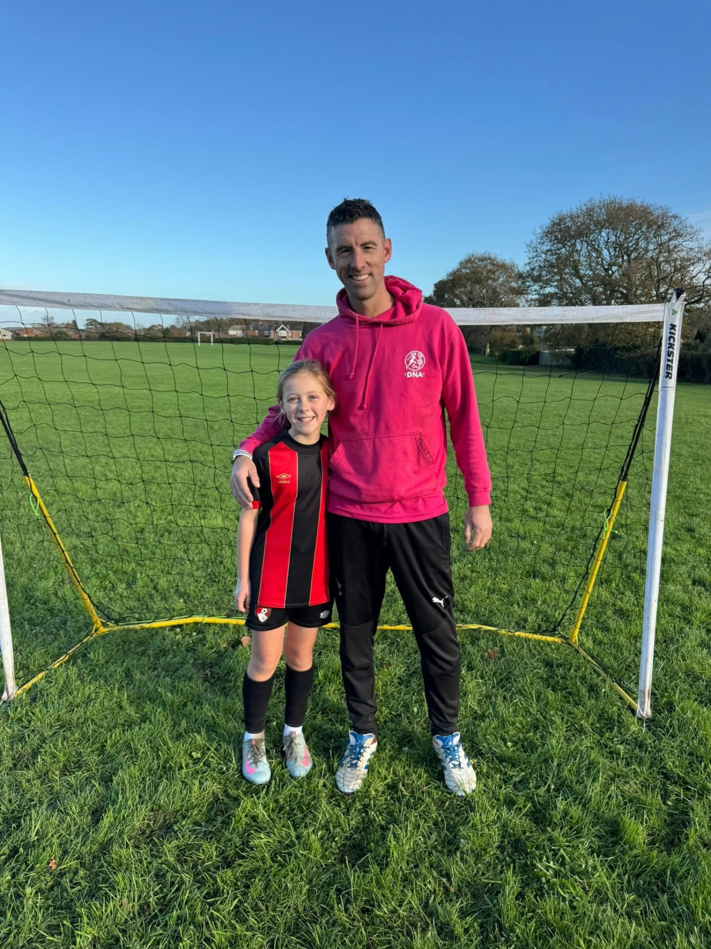 Dave Rimmer with a young player on the pitch in daylight